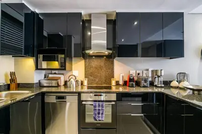 a kitchen with stainless steel appliances and black cabinets at Lux Andringa Walk Apartments in Stellenbosch