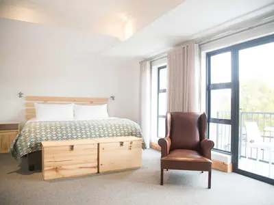 a bedroom with a bed and a chair next to a window at 7 Ackermann Place Guest House in Stellenbosch