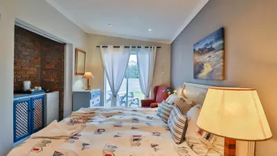 a bedroom with a bed and a lamp and a window at Da Capo in Bettyʼs Bay