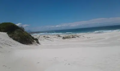 a sandy beach with the ocean in the background at Da Capo in Bettyʼs Bay