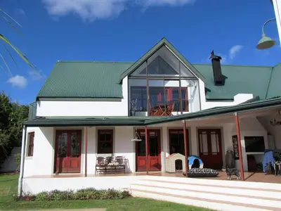 a white house with red doors and a green roof at Luxury Secure Flat Apartment in Plattekloof