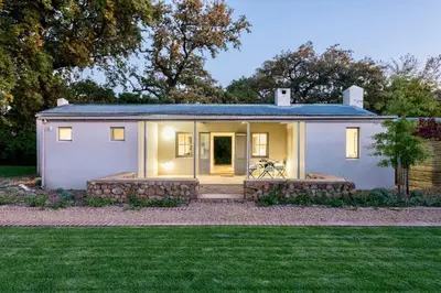 a small white house with a lawn at La Chataigne Wines & Guest Cottages in Franschhoek