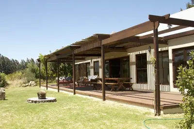 a house with a wooden deck in a yard at The Riverstone House in Romansrivier