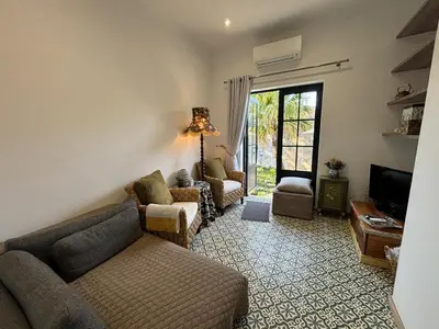 a living room with a couch and chairs and a tv at Stellenhaus Guest Cottage in Stellenbosch