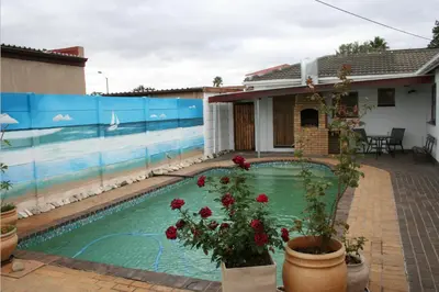 a swimming pool in front of a house with flowers at 34 On Marten Crescent in Table View
