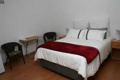 a bedroom with a bed and two chairs and a table at 34 On Marten Crescent in Table View