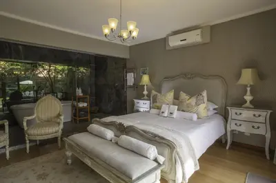 a bedroom with a large bed and a chair at Slaley Country House in Stellenbosch
