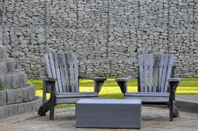 two wooden chairs sitting in front of a stone wall at Slaley Country House in Stellenbosch