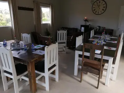 a dining room with tables and chairs and a clock at Swartberg Guest House in Caledon