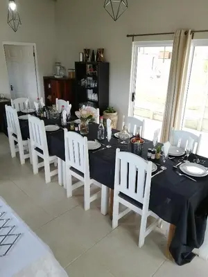 a dining table with white chairs and a black table cloth at Swartberg Guest House in Caledon