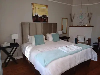 a bedroom with a large bed with towels on it at Swartberg Guest House in Caledon