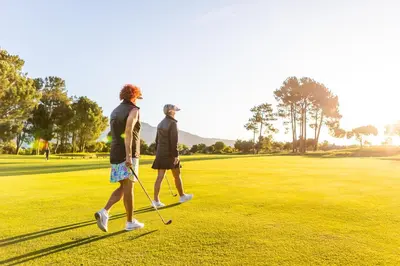 two people walking on a golf course at Pearl Valley Hotel in Franschhoek