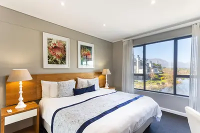 a bedroom with a large bed and a large window at Pearl Valley Hotel in Franschhoek