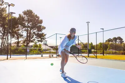 a young woman playing tennis on a tennis court at Pearl Valley Hotel in Franschhoek