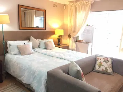 a bedroom with a bed and a couch and a mirror at Marshrose Accommodation in Bellville