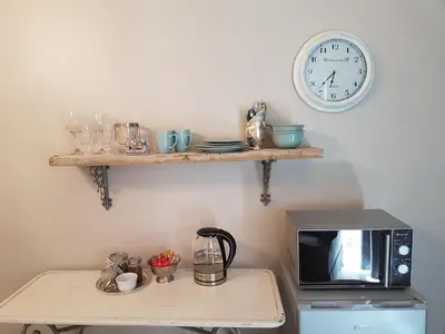 a table with a microwave and a clock on a wall at 35 on Basil in Caledon