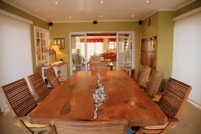 a dining room with a wooden table and chairs at Charming Fisante house in Hermanus
