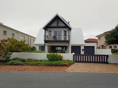 a house with a black roof and a white fence at Charming Fisante house in Hermanus