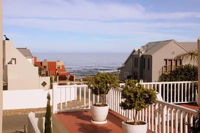 a balcony with potted plants and the ocean at Charming Fisante house in Hermanus