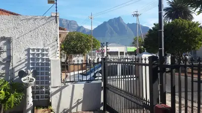 a white fence with a mountain in the background at Dancers' Cottages in Cape Town
