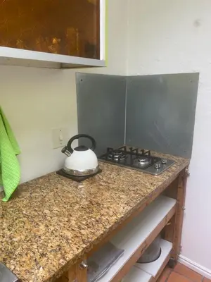 a kitchen counter with a stove with a tea kettle on it at Dancers' Cottages in Cape Town