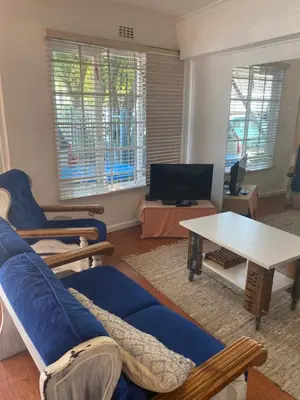 a living room with a blue couch and a table at Dancers' Cottages in Cape Town