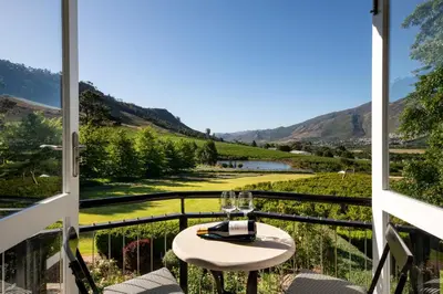 a table with wine glasses on a balcony with a view at Mont Rochelle Hotel and Vineyard in Franschhoek