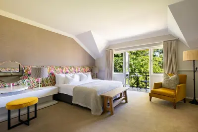 a bedroom with a bed and a chair and a window at Mont Rochelle Hotel and Vineyard in Franschhoek