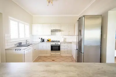 a kitchen with white cabinets and a stainless steel refrigerator at On The Rocks in Hermanus