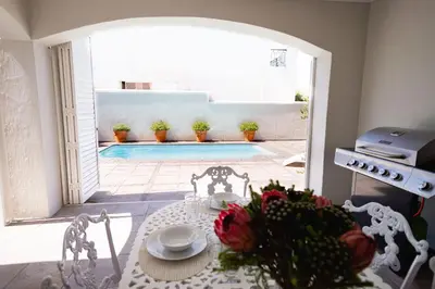 a table and chairs in a room with a pool at On The Rocks in Hermanus
