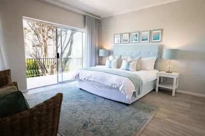 a bedroom with a large bed and a large window at On The Rocks in Hermanus