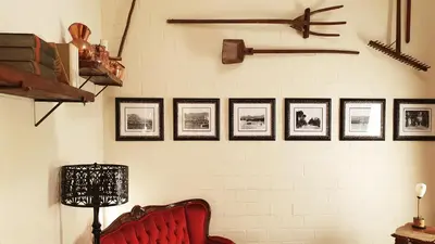 a room with a red chair and pictures on a wall at Villa Adalbert Guesthouse in Somerset West