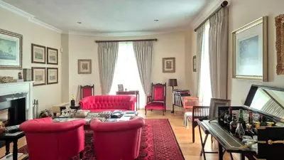 a living room with red chairs and a table at Villa Adalbert Guesthouse in Somerset West