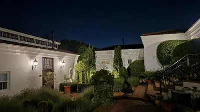 a white house with a garden at night at Villa Adalbert Guesthouse in Somerset West
