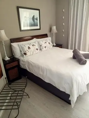 a bedroom with a large bed with white sheets and pillows at Beach front property in Strand