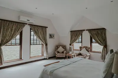 a bedroom with a large bed and windows at Cana Vineyard Guesthouse in Paarl