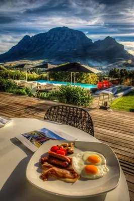 a plate of food on a table with eggs and sausage at Clouds Estate in Stellenbosch