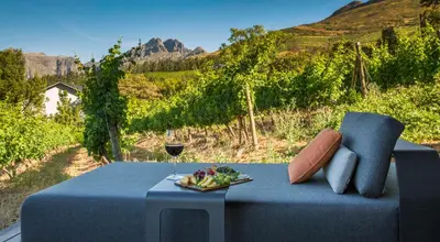 a blue table with a plate of fruit and a glass of wine at Clouds Estate in Stellenbosch
