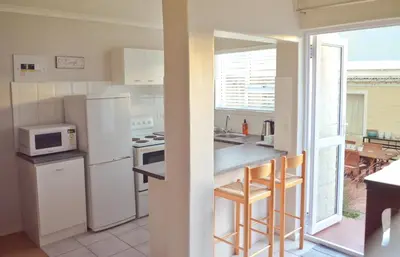 a kitchen with white appliances and a table with chairs at The Winelands Guest House in Bellville