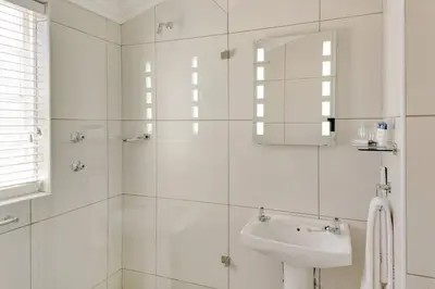 a white bathroom with a sink and a mirror at Protea Hotel by Marriott Dorpshuis & Spa Stellenbosch in Stellenbosch