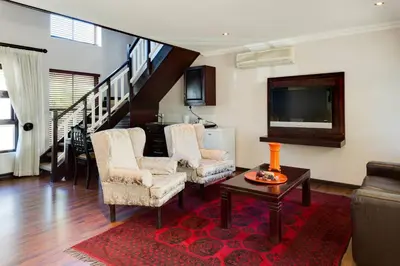 a living room with two chairs and a flat screen tv at Protea Hotel by Marriott Dorpshuis & Spa Stellenbosch in Stellenbosch