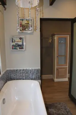 a bath tub in a bathroom with a chandelier at Eagleview Guesthouse in Hermanus