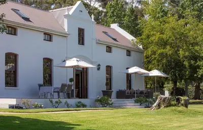 a white house with umbrellas on the lawn at Andreas Country House in Wellington