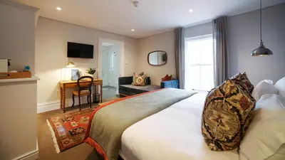 a bedroom with a large bed and a desk at Bonne Esperance Boutique Guest House in Stellenbosch