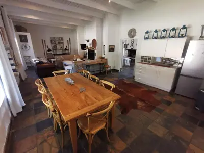 a living room with a wooden table and a kitchen at Brander View in Hermanus