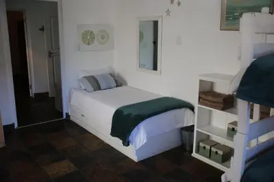 a bedroom with a white bed with a green blanket at Brander View in Hermanus