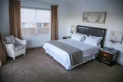 a bedroom with a bed and a chair and a window at Brander View in Hermanus