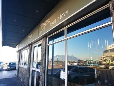 a store front with a reflection of a car in the window at Dolphin Inn Blouberg in Bloubergstrand