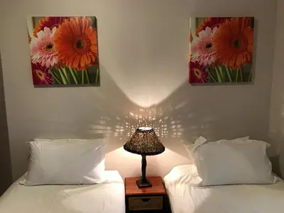 a bedroom with two beds and a lamp on a night stand at Hoogeind Manor in Somerset West