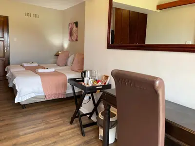 a bedroom with a bed and a table with a mirror at Hoogeind Manor in Somerset West